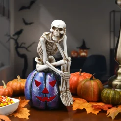 National Tree Company 11 in. Halloween Skeleton Resting on a Purple Galaxy Jack O Lantern