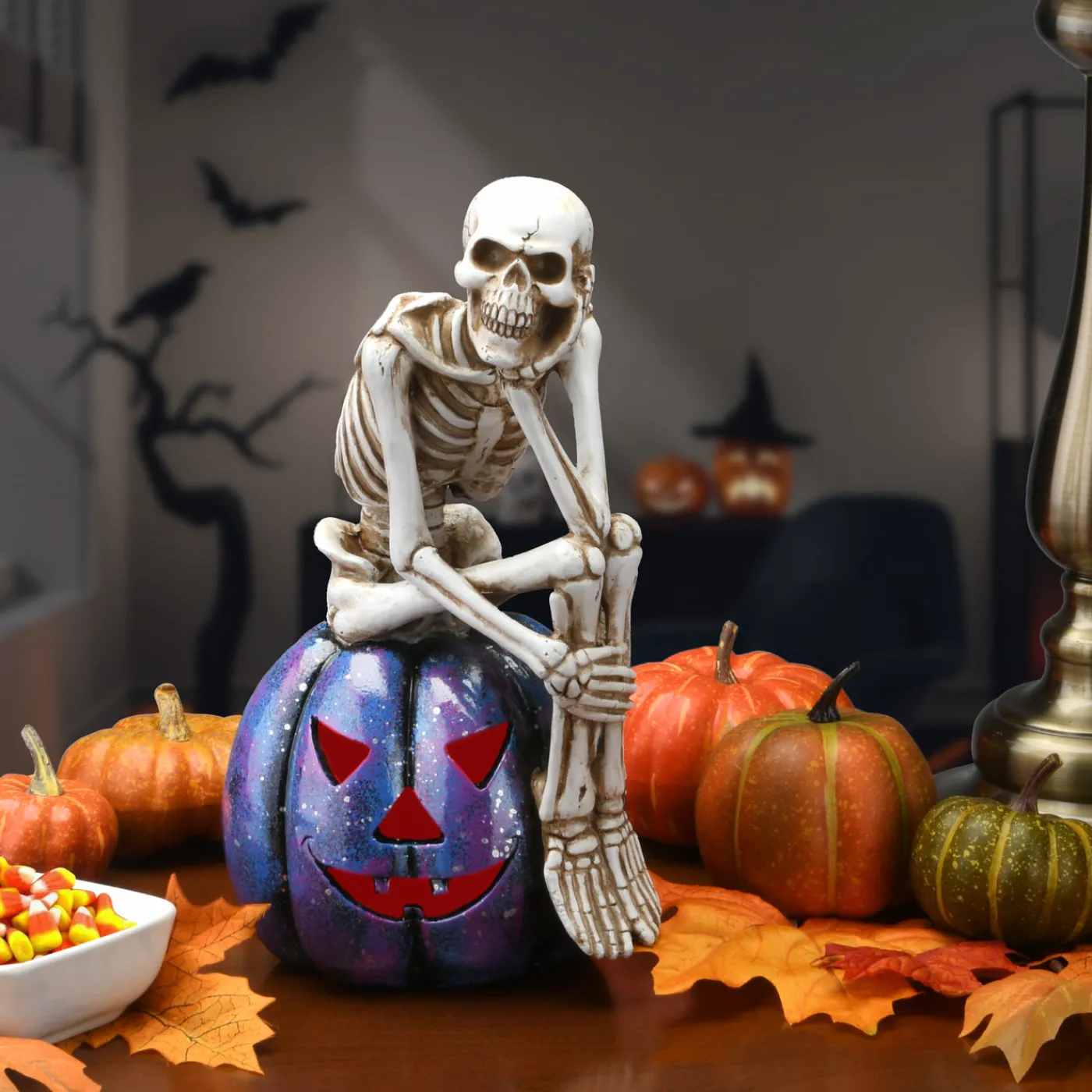 National Tree Company 11 in. Halloween Skeleton Resting on a Purple Galaxy Jack O Lantern